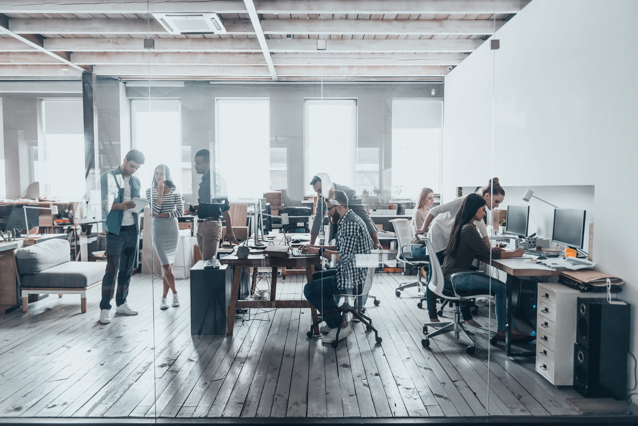 Eine Gruppe junger Geschäftsleute in eleganter Freizeitkleidung arbeitet in einem kreativen Büro zusammen